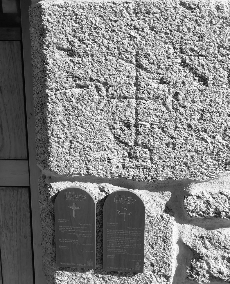Fotografía de un muro de piedra bruta de Belmonte en el que están esculpidas una cruz y, debajo, dos pequeños bloques que evocan las Tablas de la Ley.